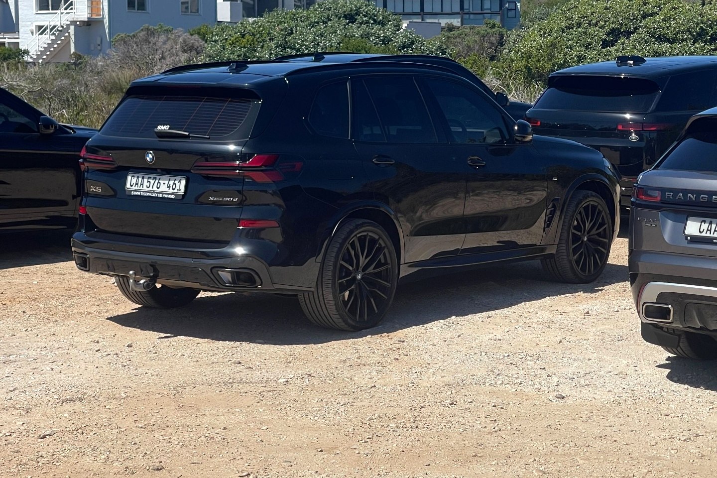Black BMW X5 parked at a coastal parking area